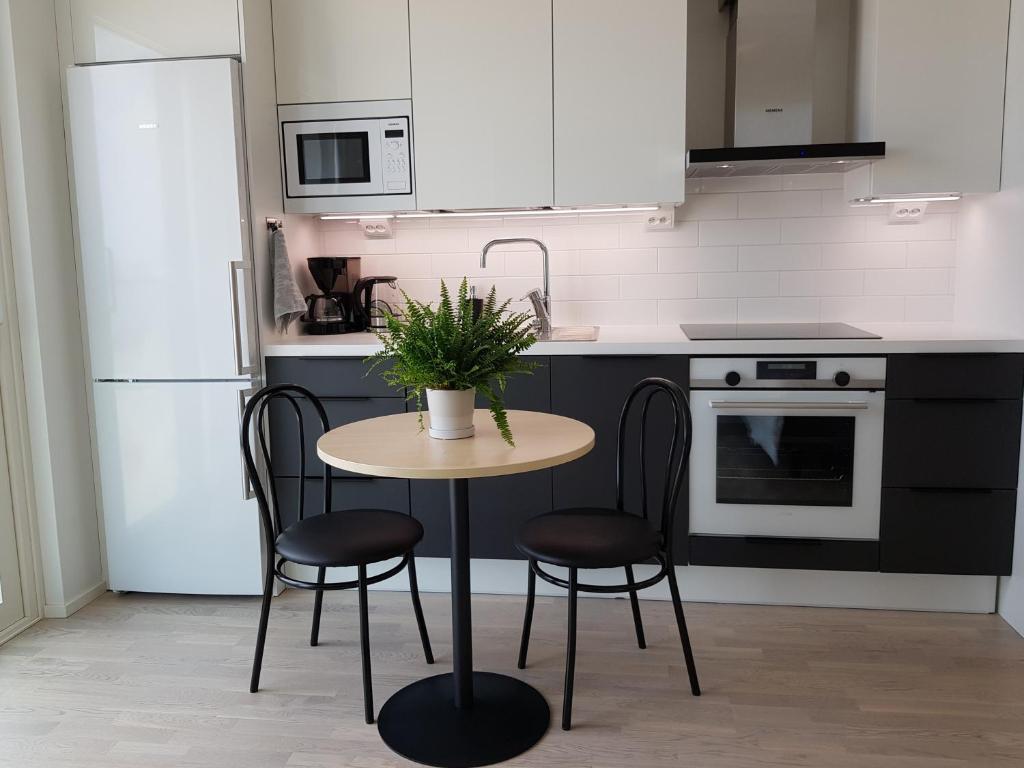 a kitchen with a table and chairs and a refrigerator at New studio in West-Pasila in Helsinki