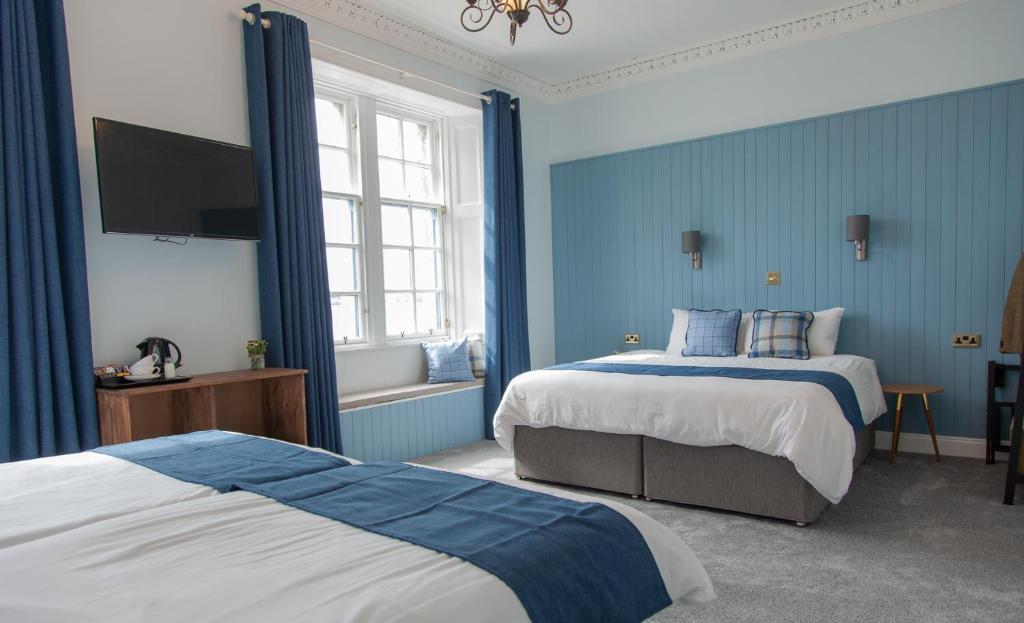 a bedroom with two beds and a flat screen tv at Coorie in Dunfermline