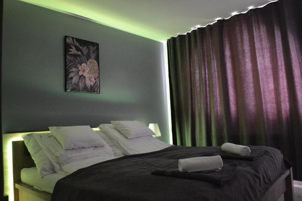 a bedroom with a large bed with two towels on it at Főnix Design Rooms in Debrecen