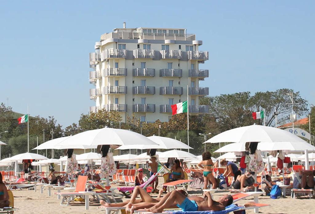 a crowd of people sitting on the beach with umbrellas at Hotel Grifone in Rimini