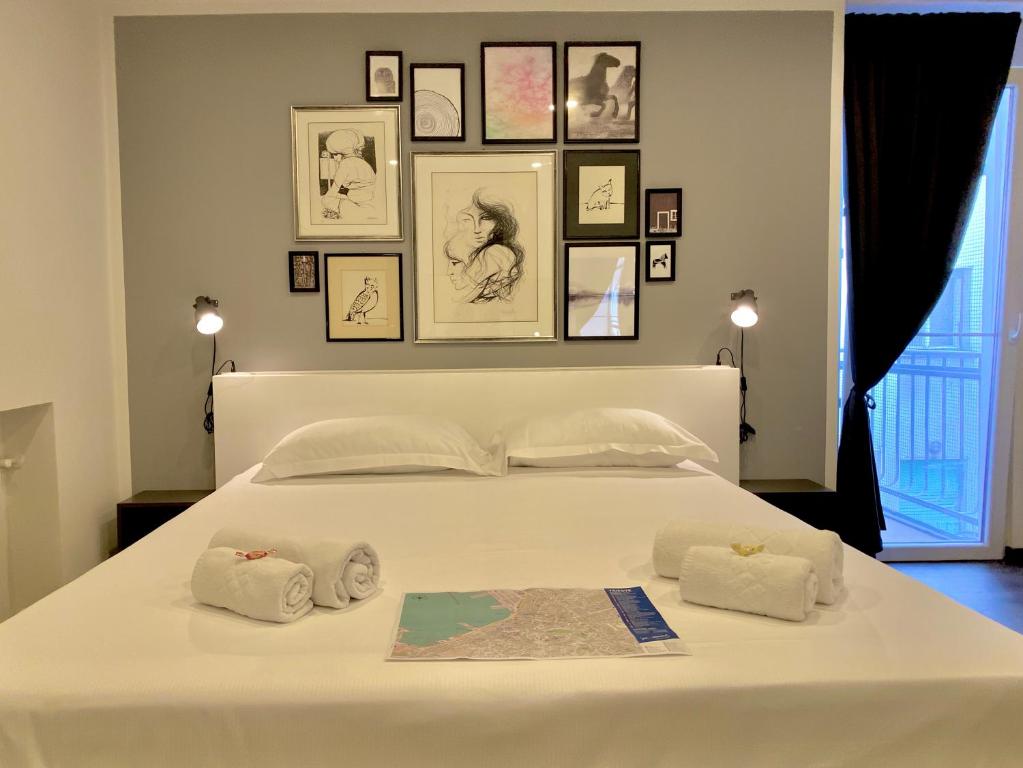 a bedroom with a white bed with pictures on the wall at Mimì Rooms&Studios in Trieste