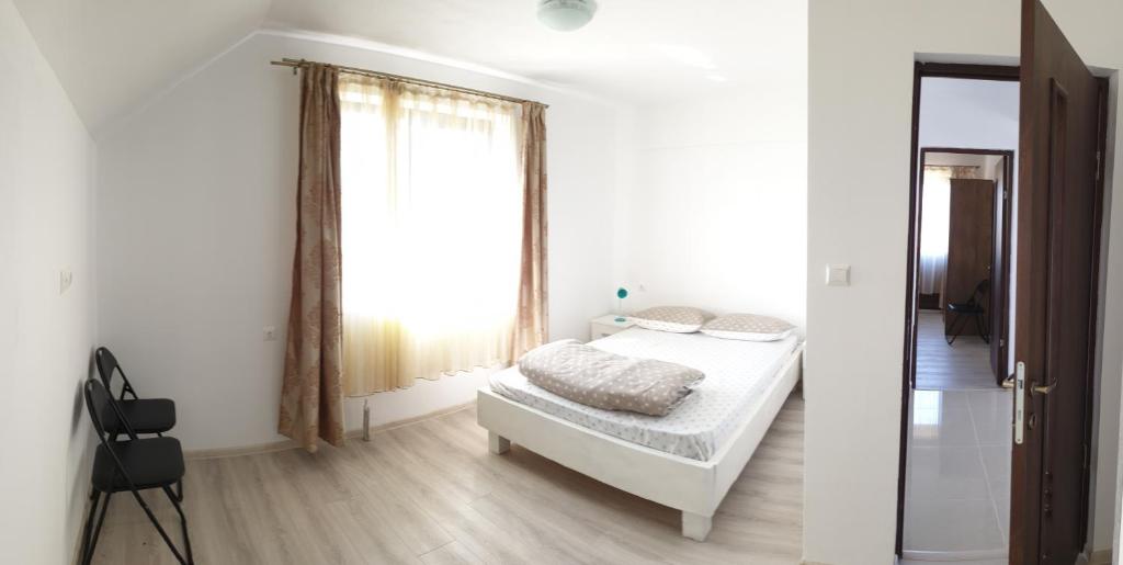 a white bedroom with a bed and a mirror at PENSIUNEA AGROTURISTICĂ ANGHELIKI in Tulcea