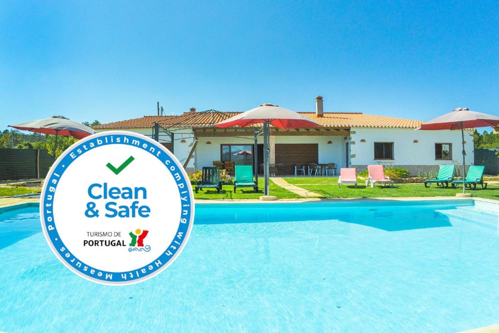 a sign in front of a swimming pool in front of a house at Montes de Praias GuestHouse in Aljezur