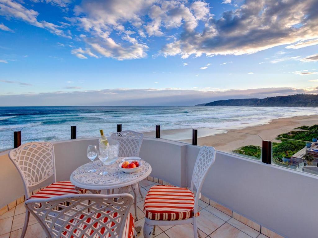 einen Tisch und Stühle auf einem Balkon mit Blick auf den Strand in der Unterkunft Dune Side Retreat in Wilderness