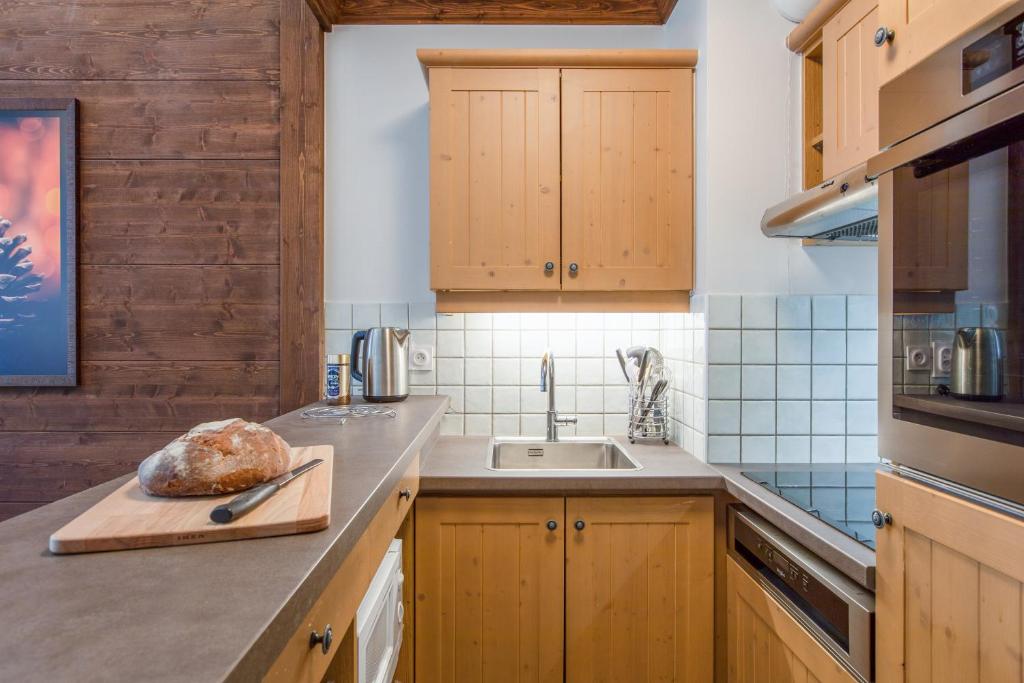 a kitchen with wooden cabinets and a loaf of bread on a cutting board at Résidence Pierre & Vacances Premium Arc 1950 Le Village in Arc 1950