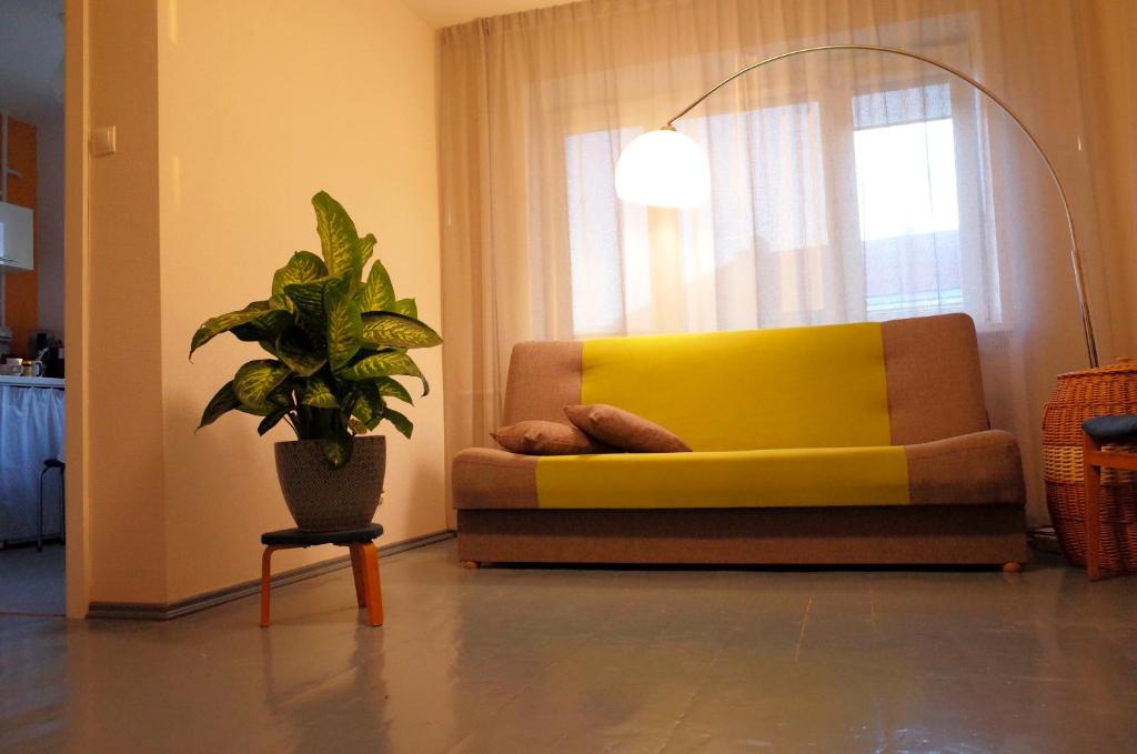 un sofá amarillo en una sala de estar con una maceta en Apartment City Heart en Valmiera