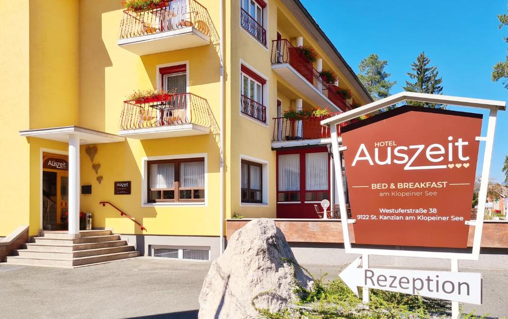 ein gelbes Gebäude mit einem Schild davor in der Unterkunft Hotel Auszeit in Sankt Kanzian am Klopeiner See