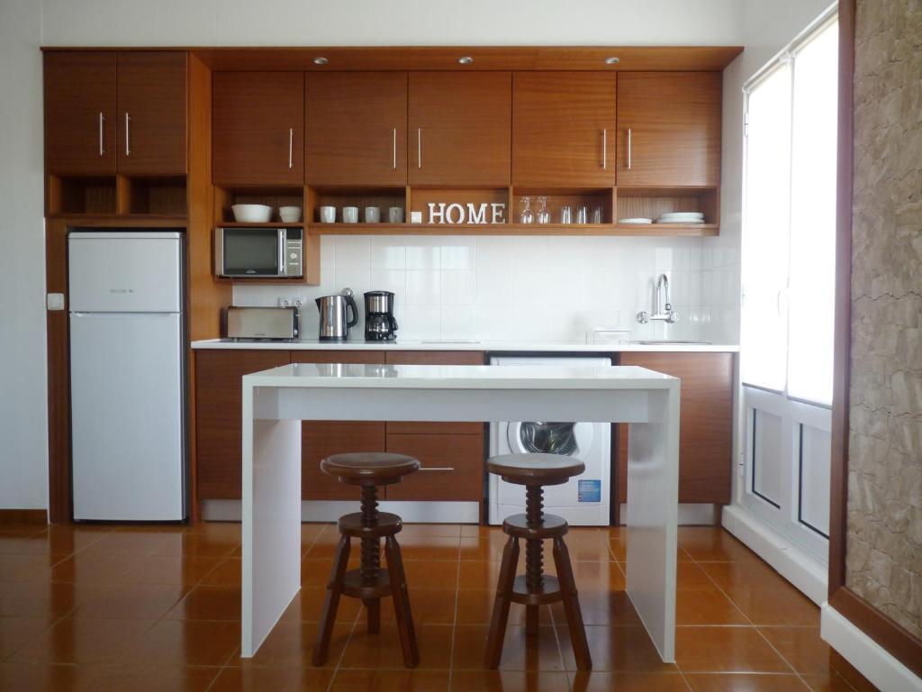 una cocina con una isla blanca y 2 taburetes en Home for Travellers ll, en Ponta Delgada