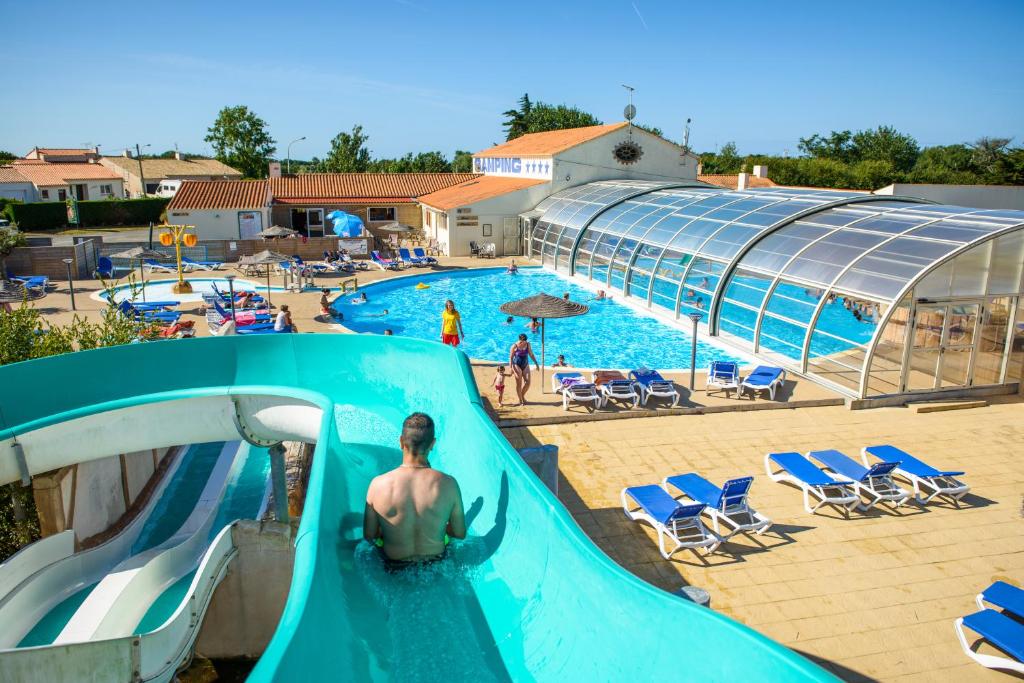 un hombre en un tobogán de agua en una piscina en Mobil Home XXL 4 chambres - Camping Le Domaine de Beaulieu, en Givrand