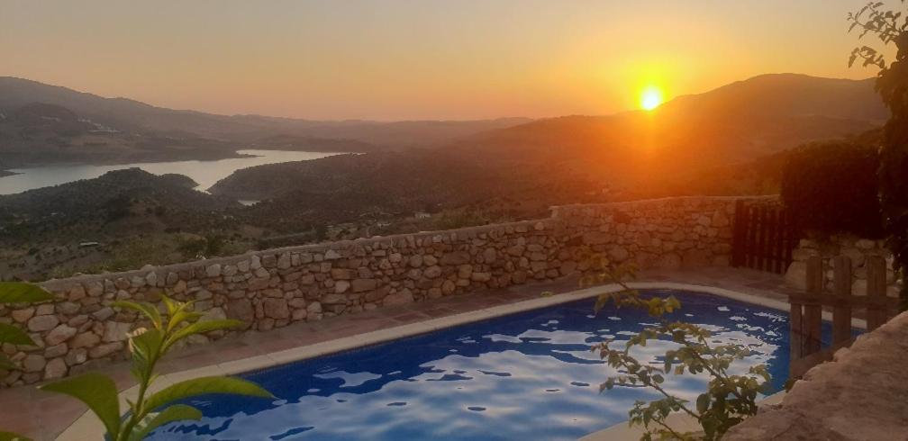 una piscina con puesta de sol en el fondo en Cortijo El Pajar, en El Gastor