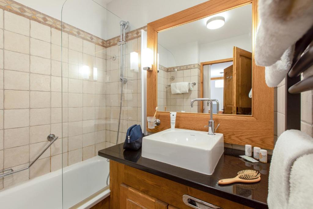 a bathroom with a sink and a tub and a mirror at Résidence Pierre & Vacances Premium Arc 1950 Le Village in Arc 1950