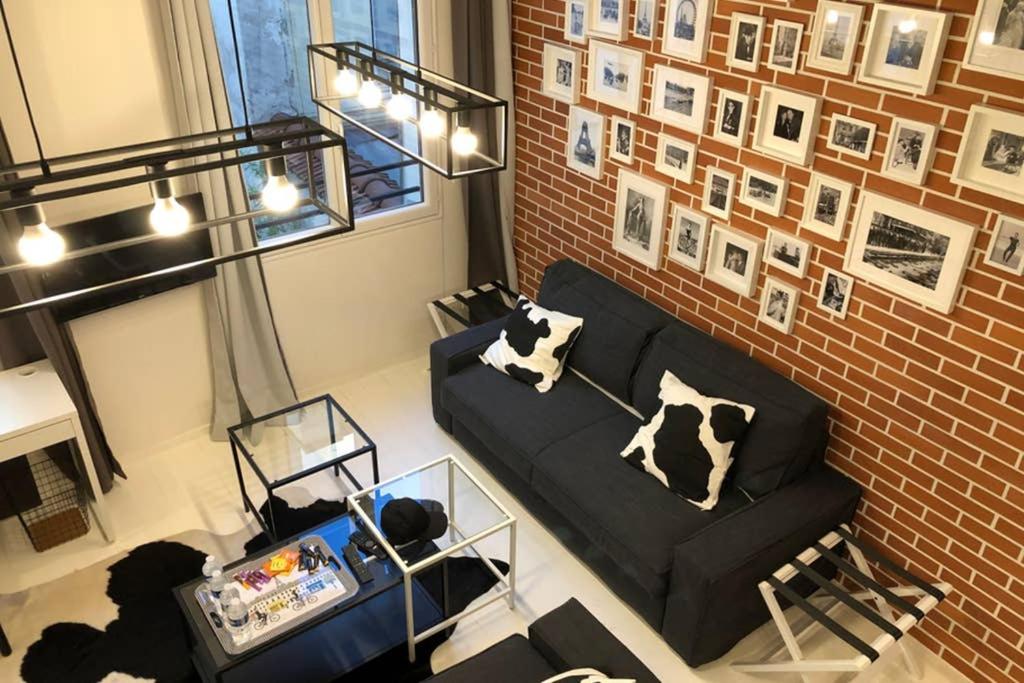 a living room with a black couch and a brick wall at Loft Nazareth Quartier du Marais in Paris