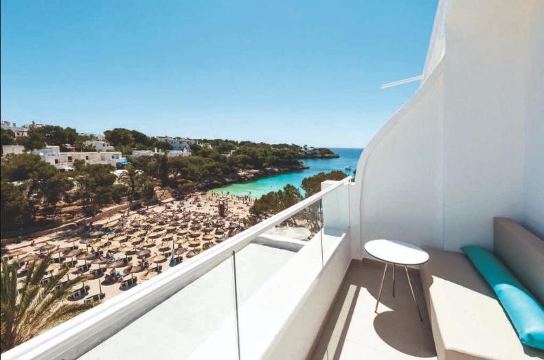 un balcón con vistas a una playa con sombrillas en Grupotel Rocador - Adults Only en Cala D'Or