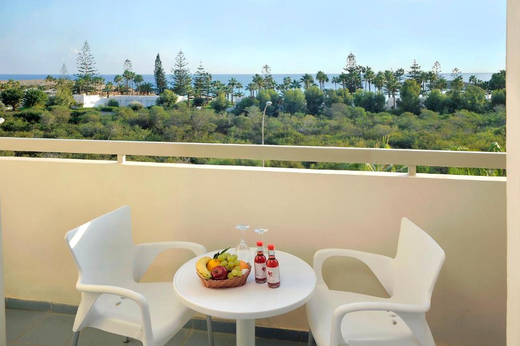 a table with chairs and a bowl of fruit on a balcony at Nissiana Hotel & Bungalows in Ayia Napa