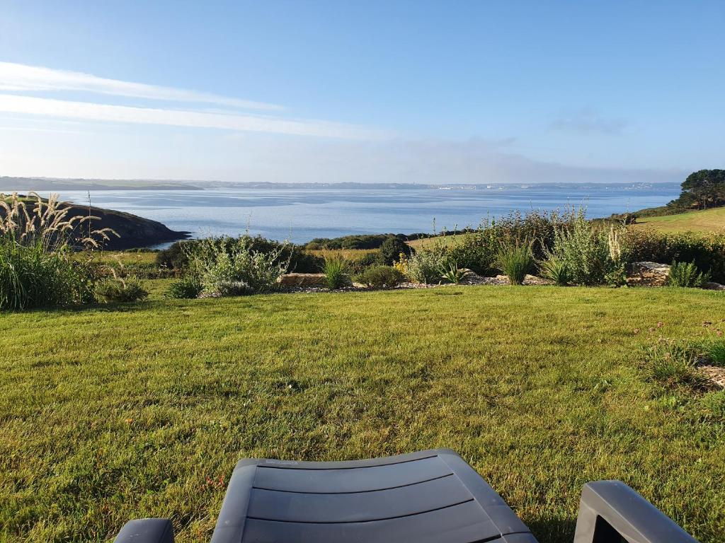 einen Stuhl auf einem Feld mit dem Ozean im Hintergrund in der Unterkunft Reflets de la Mer... in Plomodiern