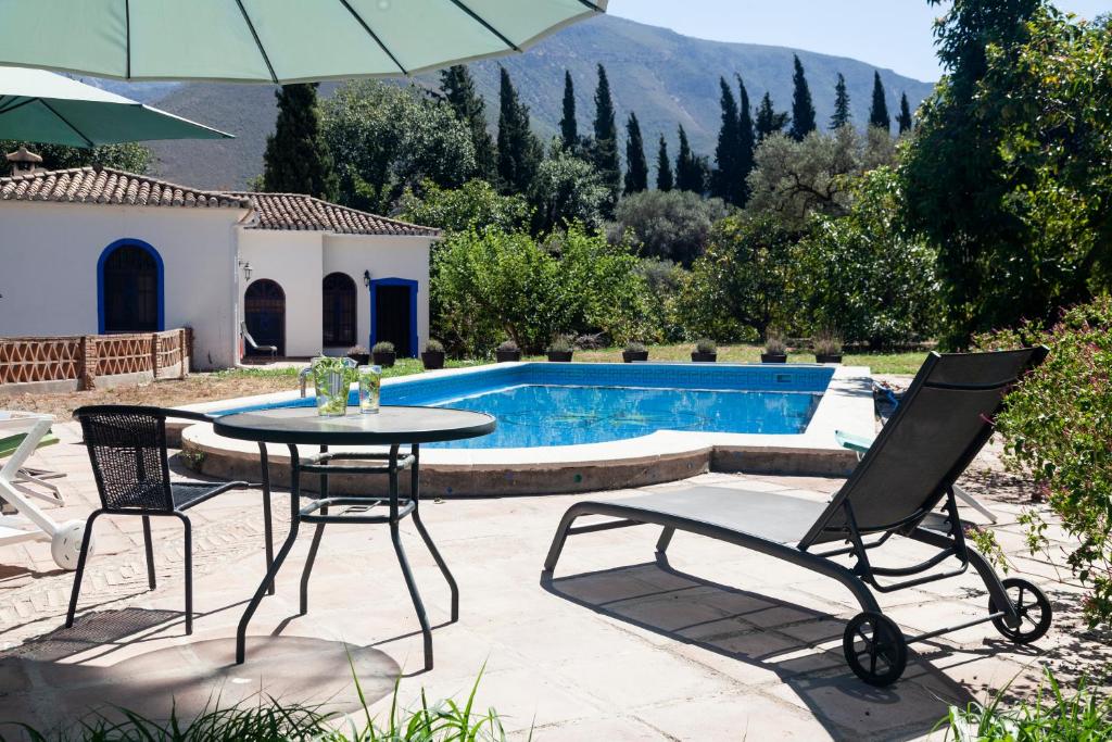 une terrasse avec une table, des chaises et une piscine dans l'établissement Cortijo el Azahar, à Órgiva