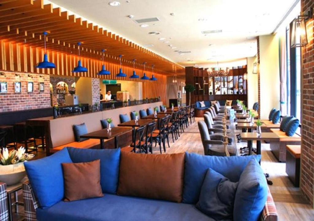 a restaurant with a blue couch and tables and chairs at Yang Ming Shan Tien Lai Resort &amp; Spa in Jinshan