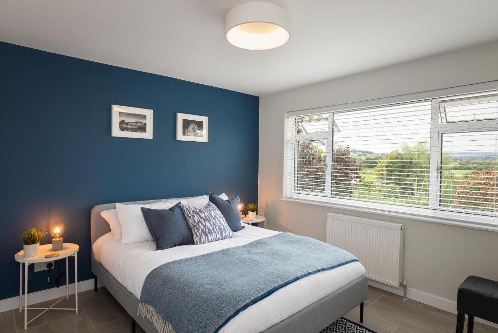 een slaapkamer met een bed met een blauwe muur bij River Retreat Apartment Exeter - River Views & Parking in Exeter