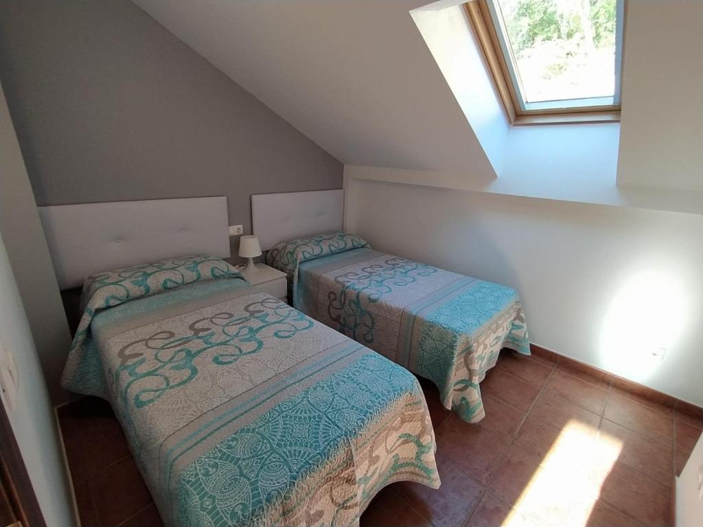 2 Betten in einem kleinen Zimmer mit Fenster in der Unterkunft Alojamiento Fuentes in Arroyo Frio