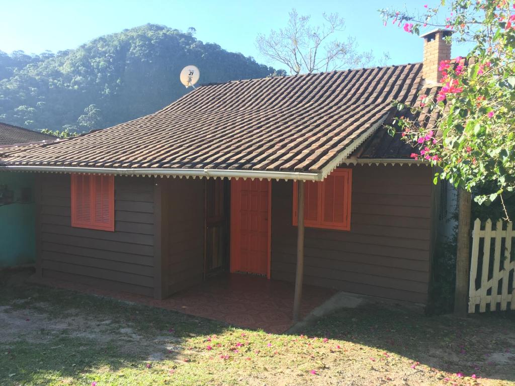 uma casa castanha com portas vermelhas e uma cerca em Casa Sossego da Montanha em Visconde de Mauá