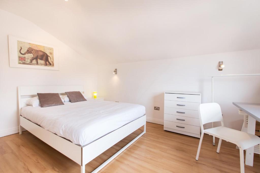 Un dormitorio blanco con una cama blanca y un escritorio. en Tooting Broadway Studios & Rooms by PrimeCityHosts, en Londres