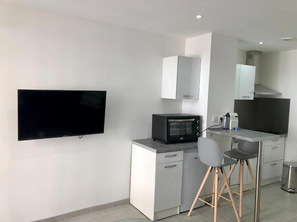 una cucina con forno a microonde e una TV a parete di Provençal Studio Netflix Appart-hotel-Provence a La Fare-les-Oliviers