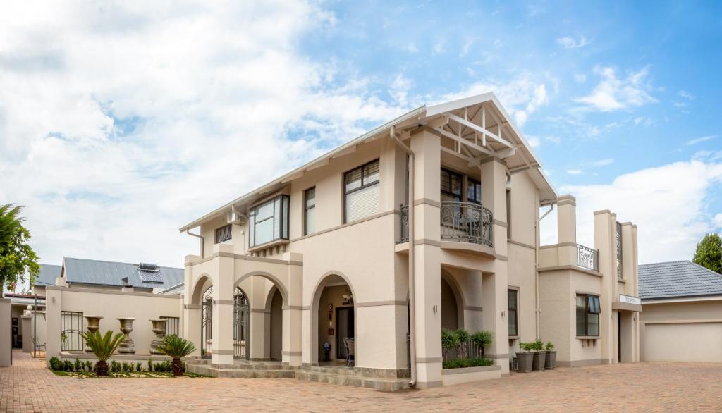 a large white house with a driveway at Adato Guesthouse in Potchefstroom