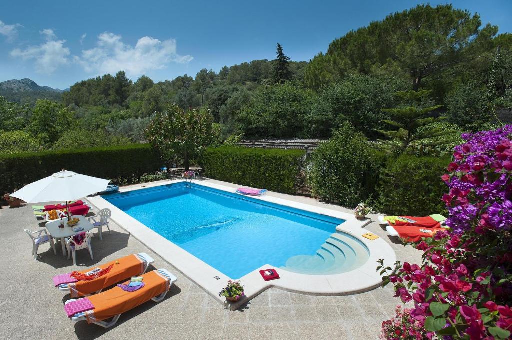 een zwembad met stoelen, een tafel en een parasol bij Villa ROTGER in Pollença