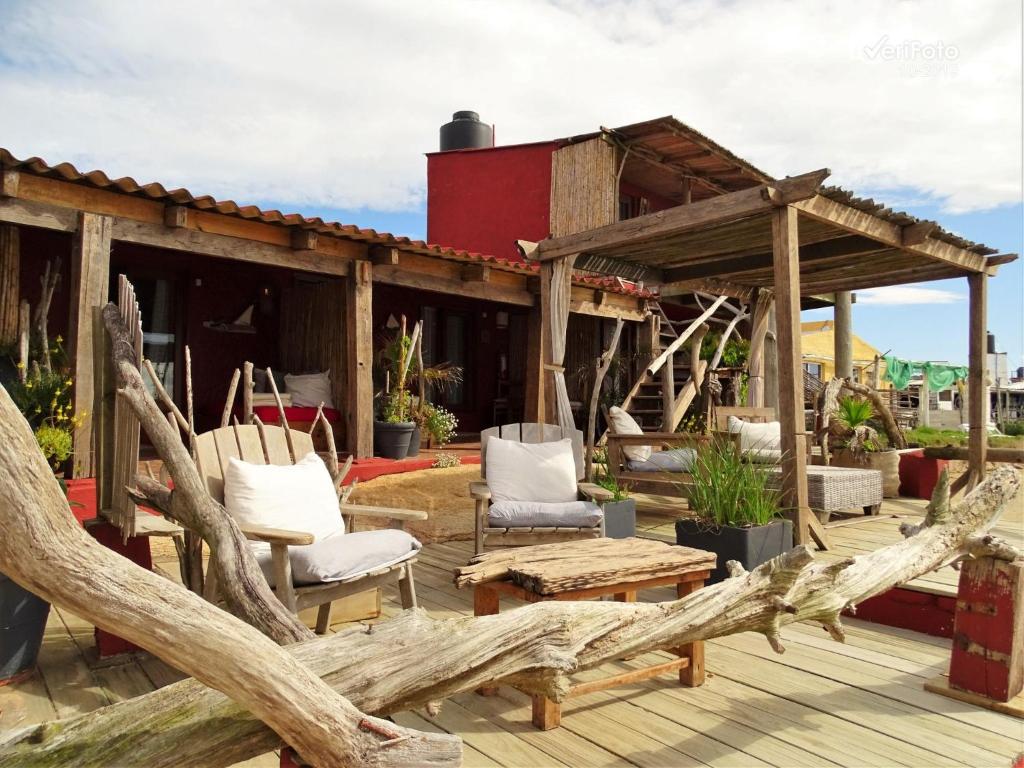 eine Holzterrasse mit Stühlen und ein Haus in der Unterkunft La Perla del Cabo in Cabo Polonio
