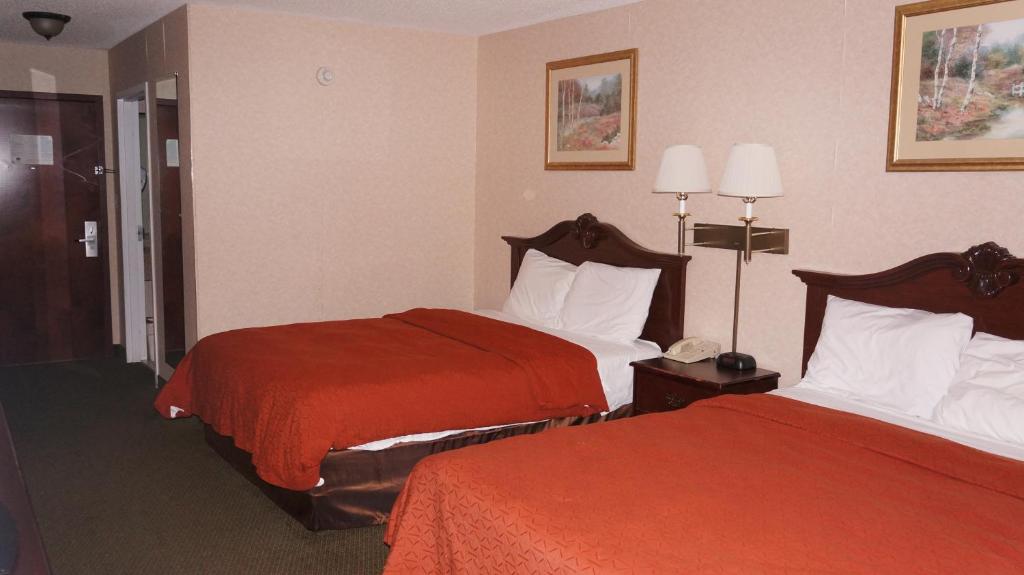 Una habitación de hotel con dos camas con sábanas rojas. en Scotland Neck Inn, en Scotland Neck