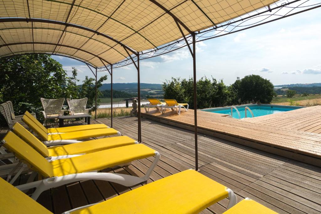 a deck with yellow chairs and a swimming pool at La petite grande in Lurs