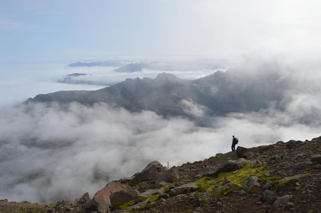 a man standing on top of a mountain in the clouds at Berunes HI Hostel in Berunes