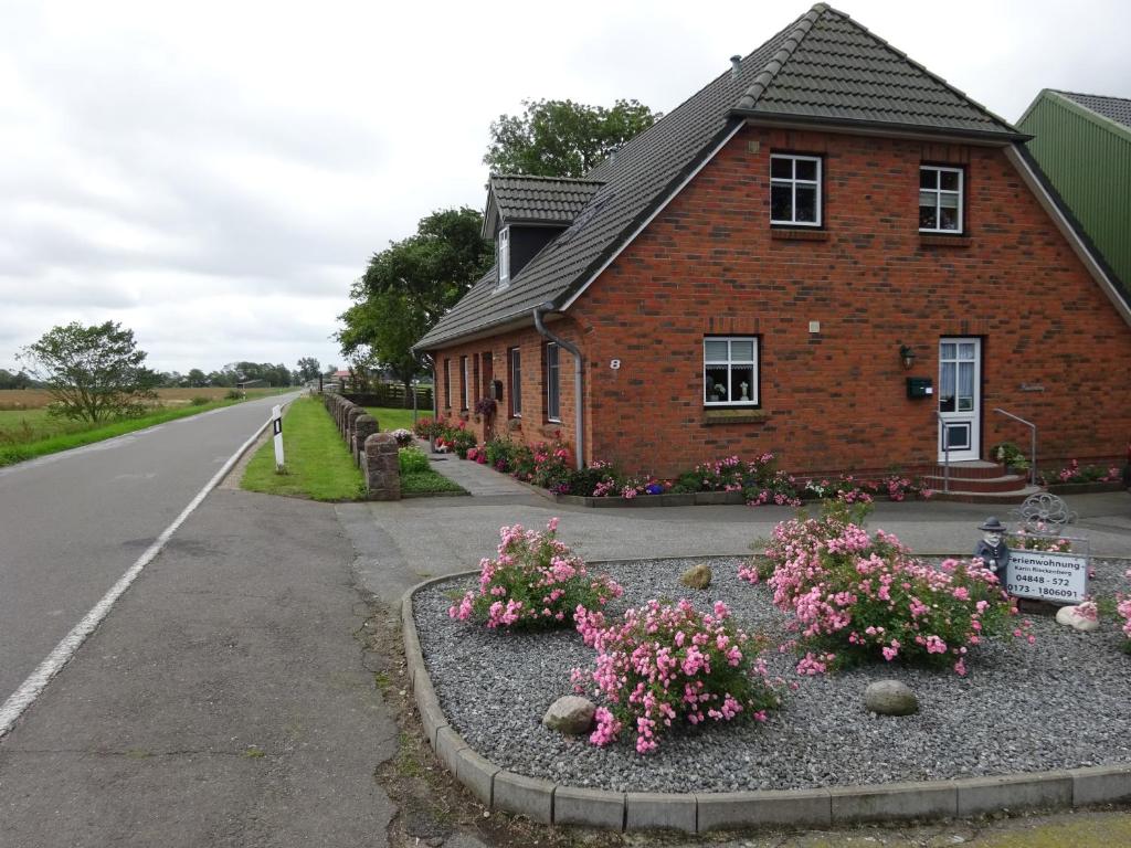 uma casa de tijolos com flores ao lado de uma estrada em Marschblick em Sudermarsch
