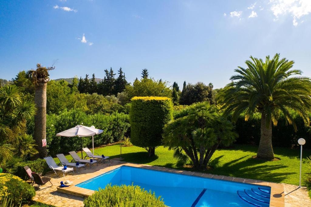 ein Swimmingpool in einem Garten mit Palmen in der Unterkunft Villa MORENO in Pollença