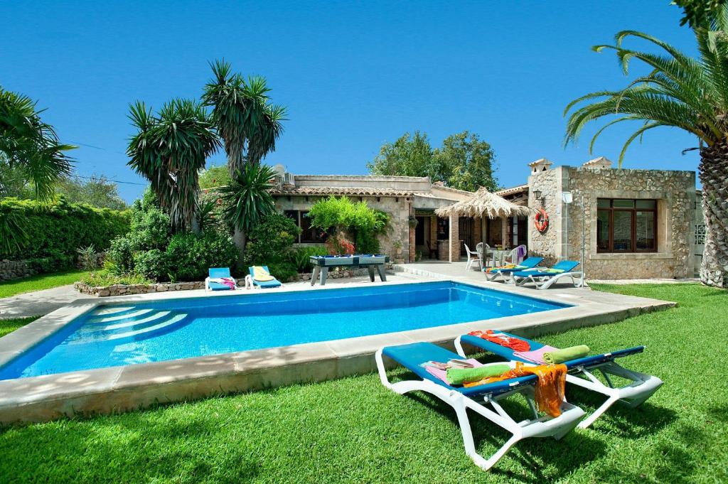 a swimming pool with two lounge chairs and a house at Villa TIA in Pollença