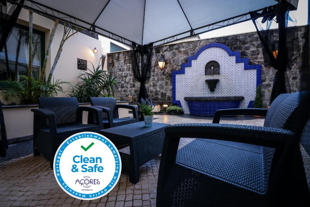 a patio with chairs and a sign that says clean and safe at Hotel Camoes in Ponta Delgada