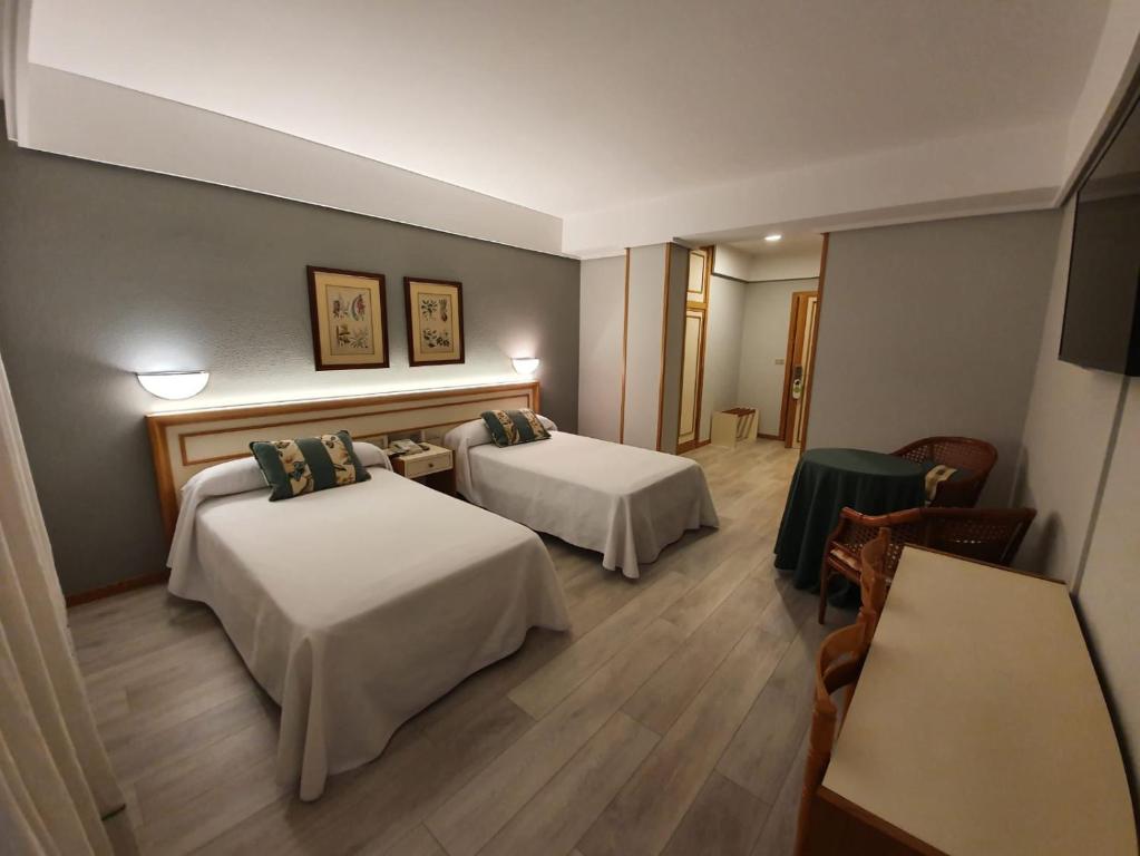 ボイロにあるHotel Alda Boiroのベッド2台とテーブルが備わるホテルルームです。