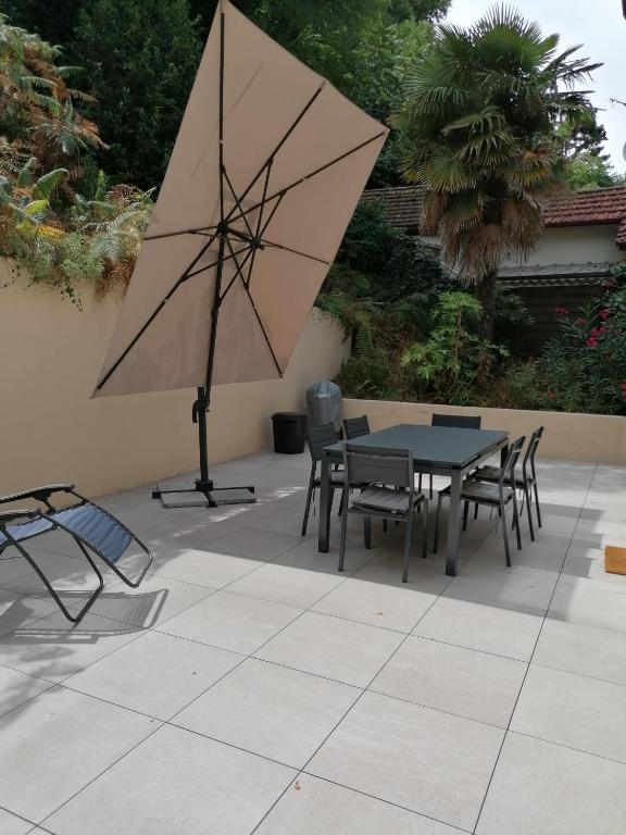 - une table, des chaises et un parasol sur la terrasse dans l'établissement Villa Rose des sables, à Arcachon