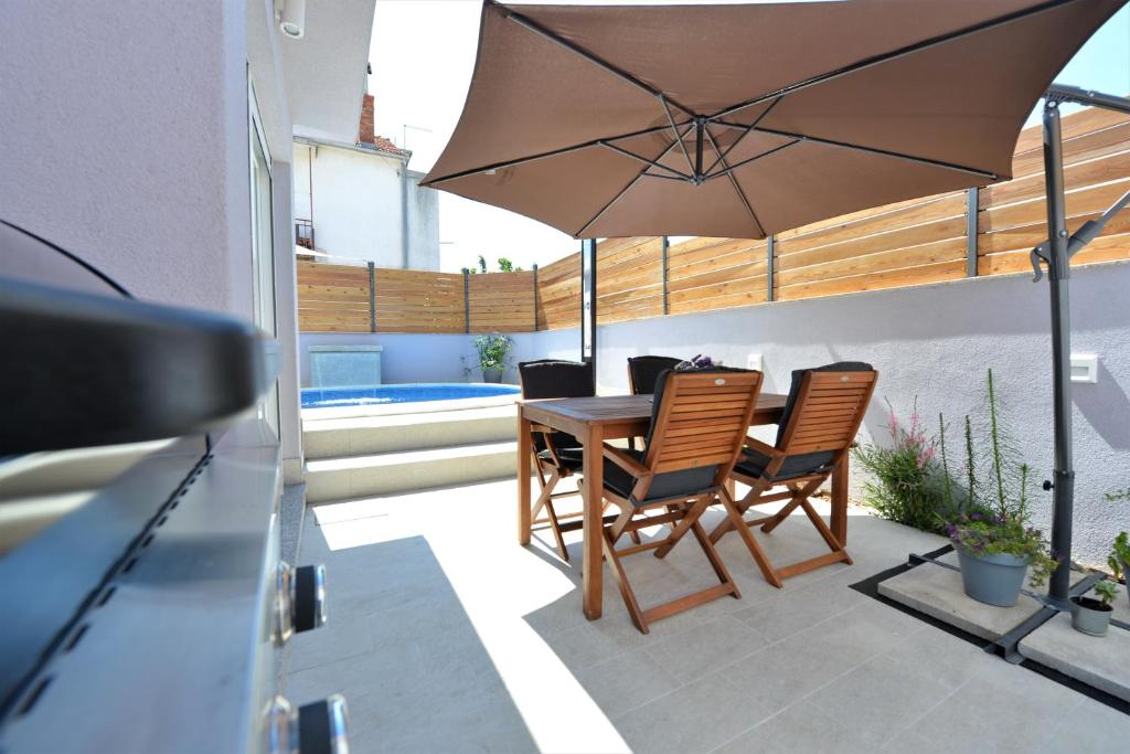 a patio with a table and chairs and an umbrella at Pop holiday house Zadar in Zadar