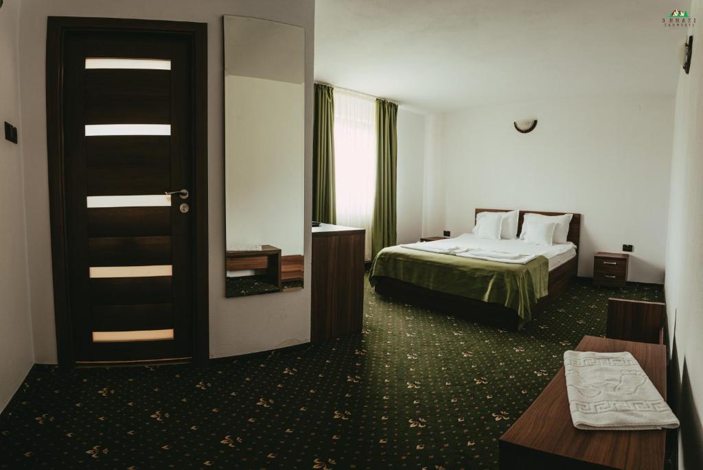 a hotel room with a bed and a mirror at Pensiunea 3 Brazi Zarnesti in Zărneşti