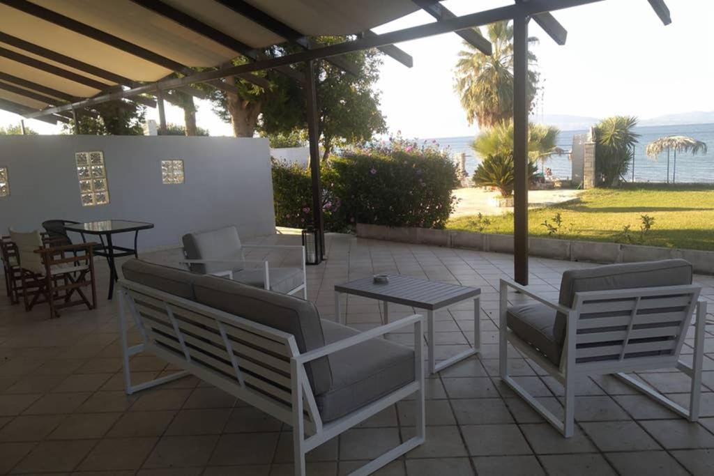 a patio with chairs and tables with a view of the ocean at Kalypso relaxing shelter in Arkítsa