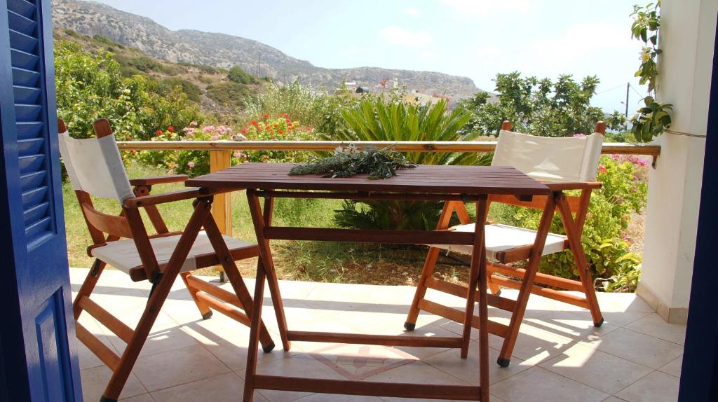 een houten tafel en 2 stoelen op een balkon bij Pleiades Apartments in Lefkos Karpathou