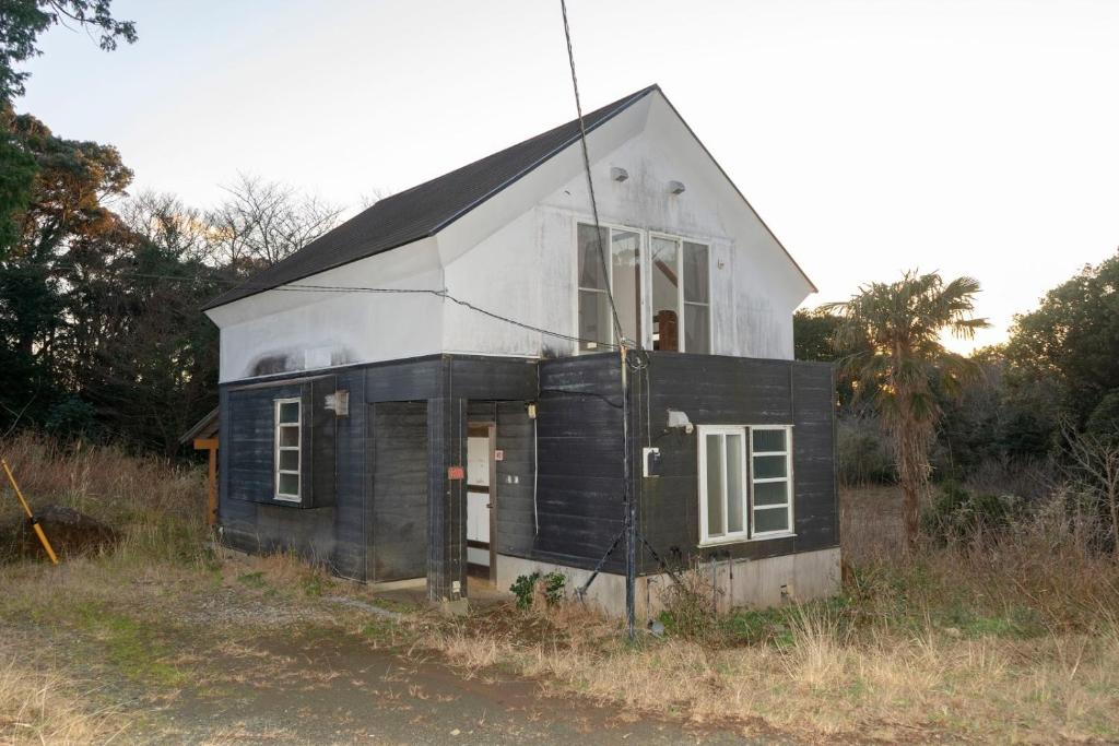 une petite maison noire et blanche dans un champ dans l'établissement Minamiizu Land Hopia - Vacation STAY 83984, à Ihama