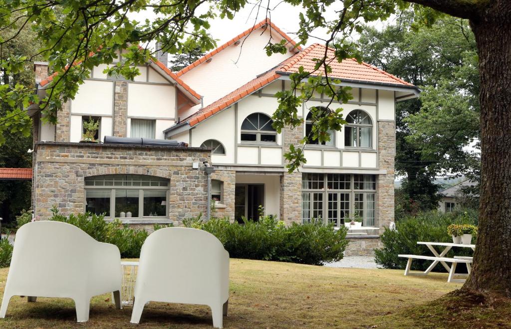 duas cadeiras brancas sentadas em frente a uma casa em La Vigie, Spa em Spa