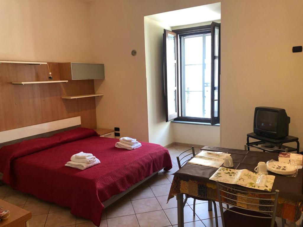 una camera con letto rosso, tavolo e televisore di Monolocale in Via Poerio a Catanzaro