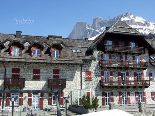 a large stone building with balconies and a mountain at SUITE25 GOLFHOTEL in Carezza al Lago