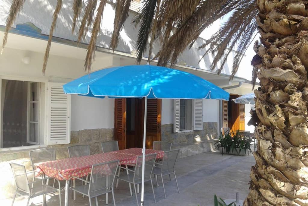 une table avec un parapluie bleu devant une maison dans l'établissement RIBARIĆ, à Banjol