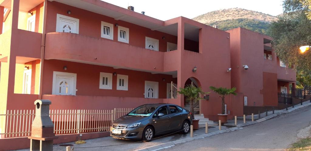 a car parked in front of a red building at Apartments Danilo Kažanegra in Sveti Stefan