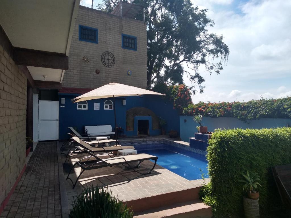 a patio with chairs and an umbrella next to a pool at La Casa del Volcan in Tlayacapan