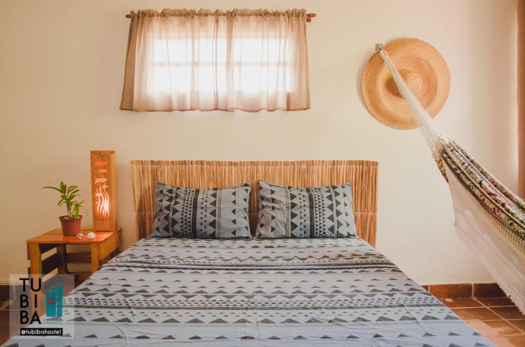 a bedroom with a bed with blue and white sheets at Tubiba Hostel in Tamandaré